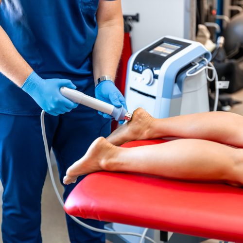 Shock wave therapy, the magnetic field, rehabilitation, physiotherapist doctor performs surgery on a patient's heel.